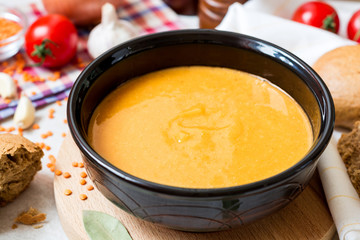 Red lentil cream soup in dark ceramic bowl