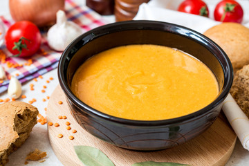 Red lentil cream soup in dark ceramic bowl