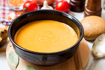 Red lentil cream soup in dark ceramic bowl