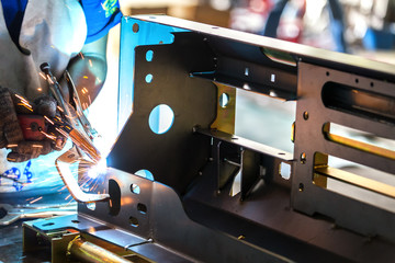 Worker welding the sheet metal part by manual