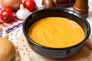 Red lentil cream soup in dark ceramic bowl