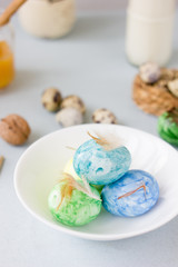 Green, yellow and blue easter eggs on ceramic bowl, bright and airy shot.