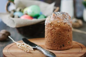 Easter cake standing on board against the basket with easter eggs.