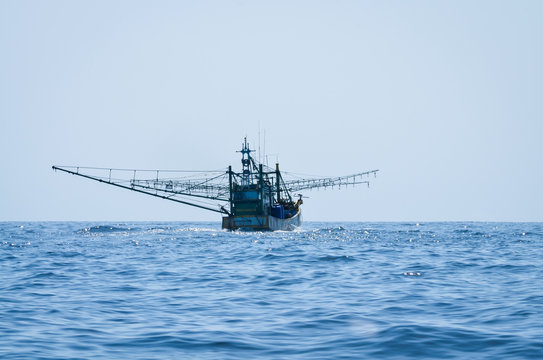 Fototapeta blue Fishing trawler on the ocean water