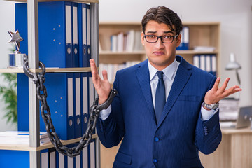 Young man standing next to the shelf with folders