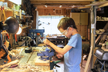 boy in protective glasses working with a file. young carpenter working in a workshop