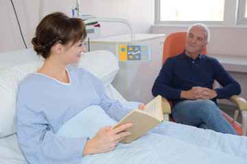 Female patient in bed, relative sat in chair