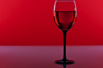 Naklejka na ściany i meble Glass of red french wine on a red background