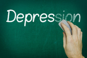 Hand erasing the word DEPRESSION written on blackboard