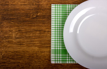 Empty plate and towel on the wooden table background