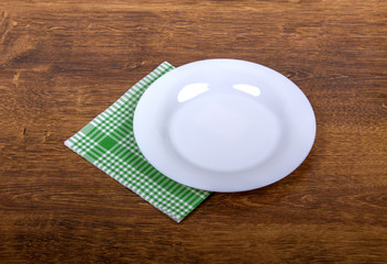 Empty plate and towel on the wooden table background