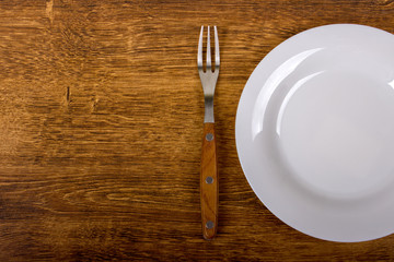 empty white plate and fork on wooden background!