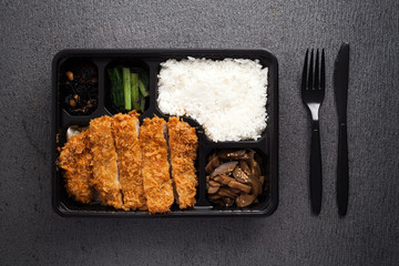 Japanese food tonkatsu rice and vegetable take away on table background