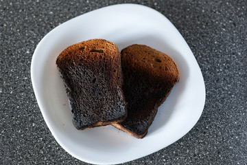 Burnt bread from the toaster on a plate. Bad cooking