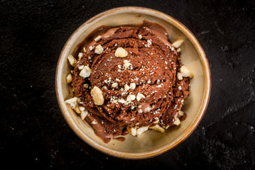 Chocolate ice cream with pieces of chopped nuts. On the black concrete stone table, top view copy space