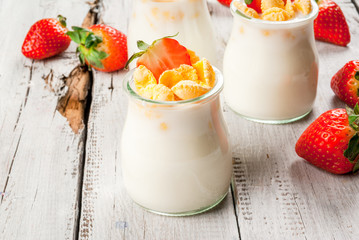 Summer light breakfast: homemade organic yogurt with cornflakes and fresh strawberries. On a white rustic wooden table copy space
