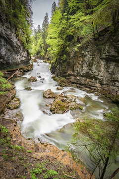Gebirgsbach mit Stromschnellen fließt zwischen steilen Felswänden