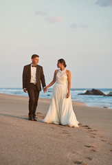 Bride and groom walking on beach