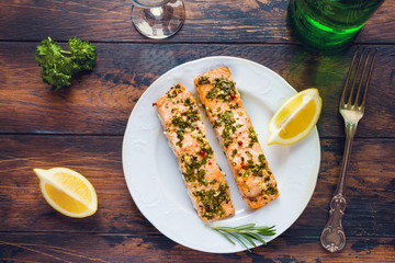 Salmon roasted in an oven with a butter, parsley and garlic. Portion of cooked fish and fresh lemon...