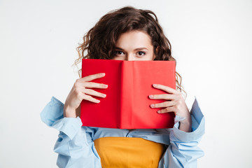 Young woman covering her mouth with book