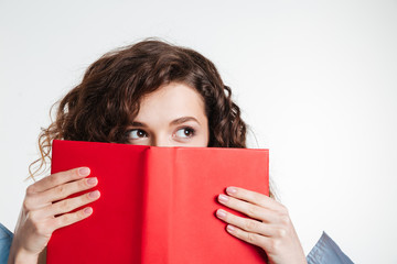 Portrait of a young woman covering her mouth with book