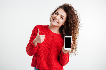 Smiling young woman showing blank smartphone
