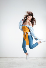 Fototapeta na wymiar Full length of pretty woman in shirt jumping in studio