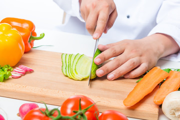 Chef cuts the cucumber salad carefully on a wooden cutting board