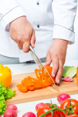 Chef cuts the peppers into thin slices on a wooden board close up