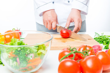 Obraz na płótnie Canvas Chef in uniform cuts the organic vegetables in a glass bowl