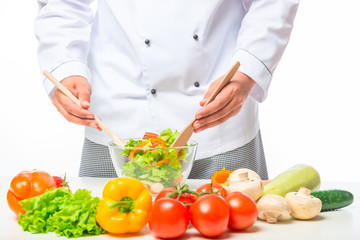 hands chef stirring with a wooden spoon vegetable salad in a bowl on a table