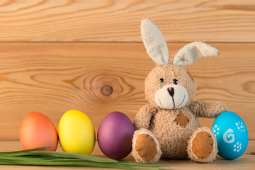 toy rabbit with Easter eggs on wooden background close-up