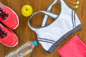 on a dark wooden floor sports objects and women's clothing top view