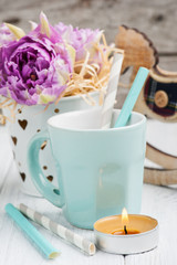 pink tulips, blue cup, straws, lit candle and rocking horse
