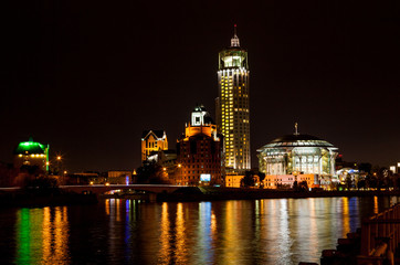 Night panorama of the Moscow House of Music is reflected in the Moscow river, Russia.