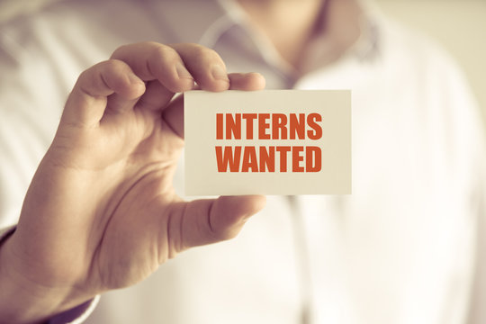 Businessman holding INTERNS WANTED message card