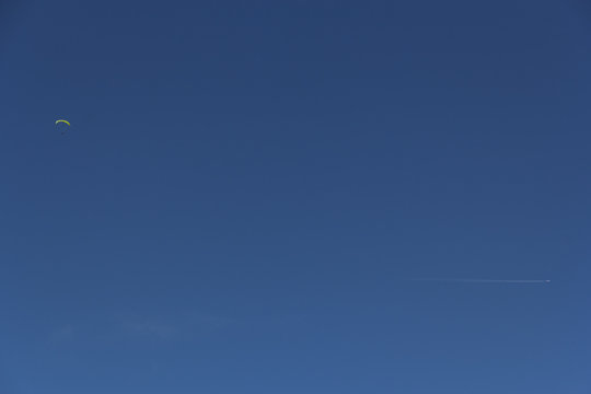 Paragleiter und Flugzeug am blauen Himmel