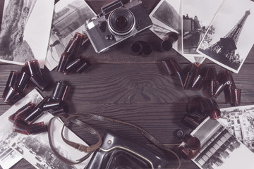 Old camera, film and black and white photographs are on the dark
