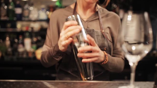 barmaid with shaker preparing cocktail at bar