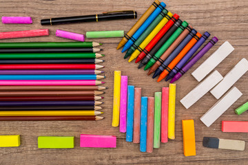 School Supplies - colored chalks and  pencils on a wooden background.