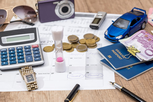 time to travel - passport, money, camera, watch, calculator, glasses, calendar toy car on wooden table.