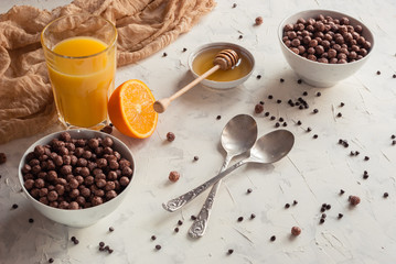 Chocolate flakes with honey and orange juice for breakfast on a white background. Two portions.