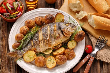 Foto auf Acrylglas Fish Gegrillter Fisch mit Baguette und Gemüse auf dem Teller