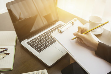 female manager putting his ideas and writing business plan at workplace,woman holding pens and papers, making notes in documents, on the table in office,vintage color,morning light ,selective focus.