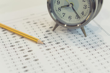  pencil sitting on a test bubble sheet and alarm clock, optical form of an examination,Answer sheet with pencil,Standardized test form with answers bubbled and a black pencil
