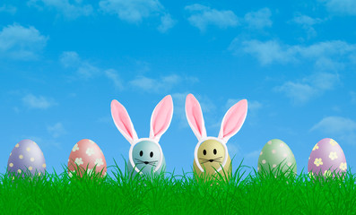 colorful pastel easter eggs with bunny ears in grass with blue sky background, copy space