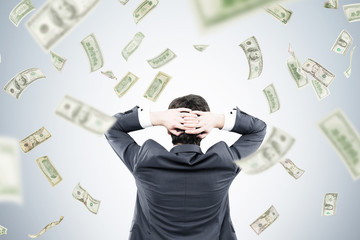 Man with hands behind head and dollars falling