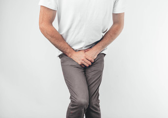 A man holding his penis with on the white background. Wants to go to the toilet.