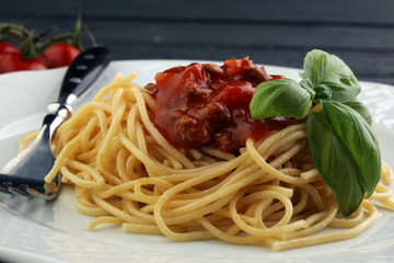 Plate of delicious spaghetti Bolognaise or Bolognese with savory minced beef and tomato sauce garnished with parmesan cheese and basil