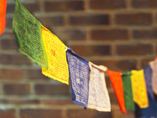 Multicolored Tibetan prayer flags lungta against a brick wall background. Red, green, white, blue...